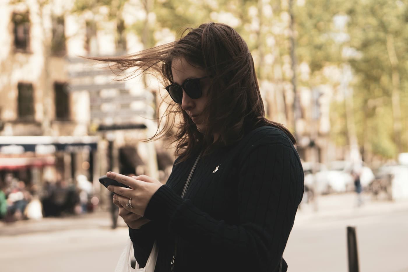 Mulher caminhando na rua enquanto olha para o celular