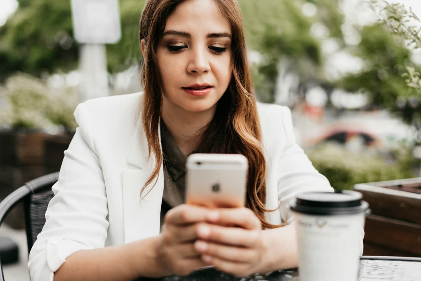 Mulher sorrindo enquanto usa o celular em um café