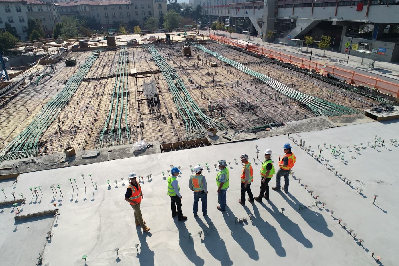 Equipe de capacete e colete observando um grande canteiro de obras