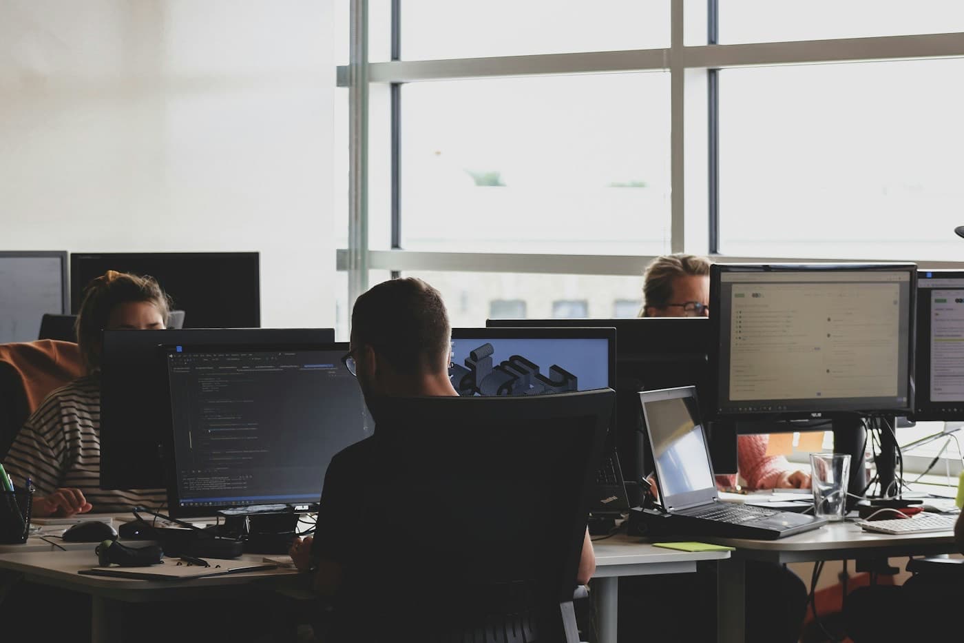 Equipe de tecnologia trabalhando em frente a vários monitores