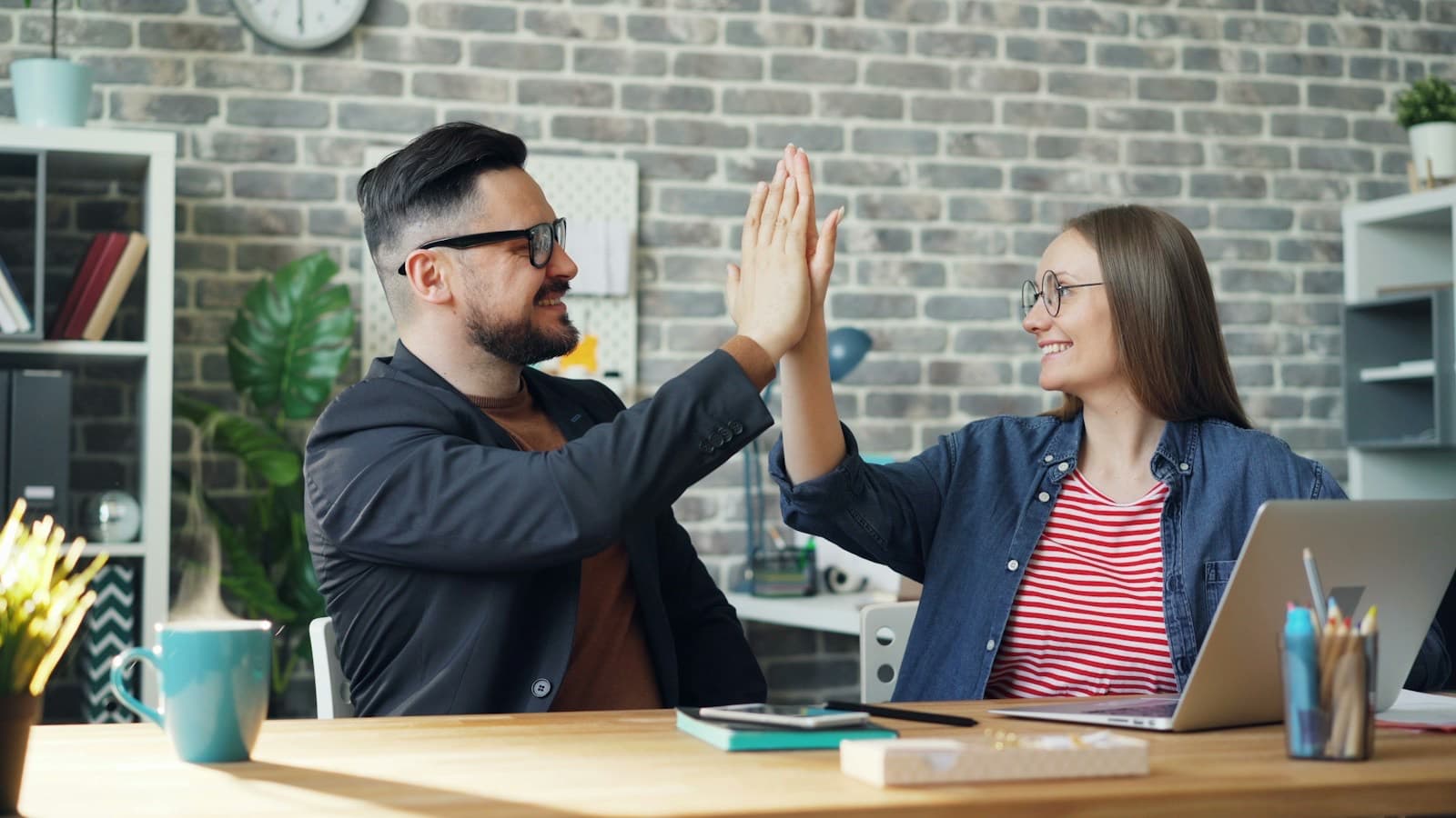Colegas de trabalho comemorando com um toque de mãos no escritório