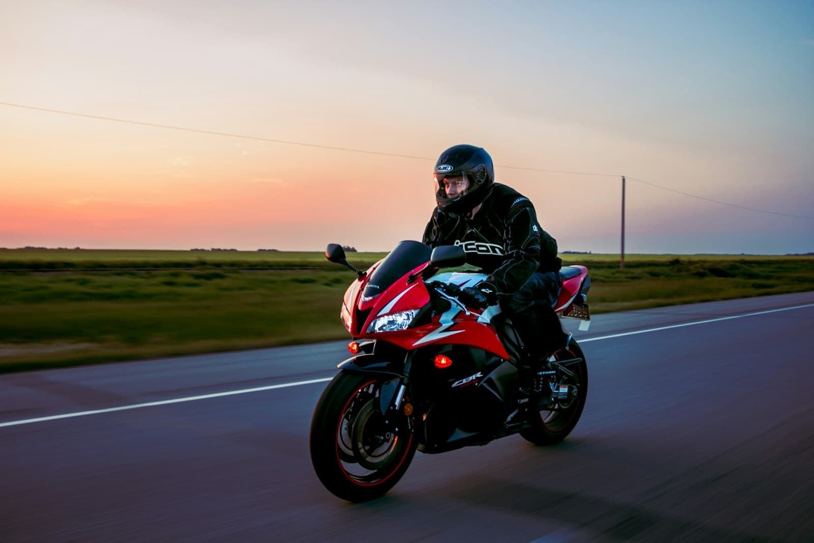 Motociclista de capacete pilotando em uma estrada ao pôr do sol