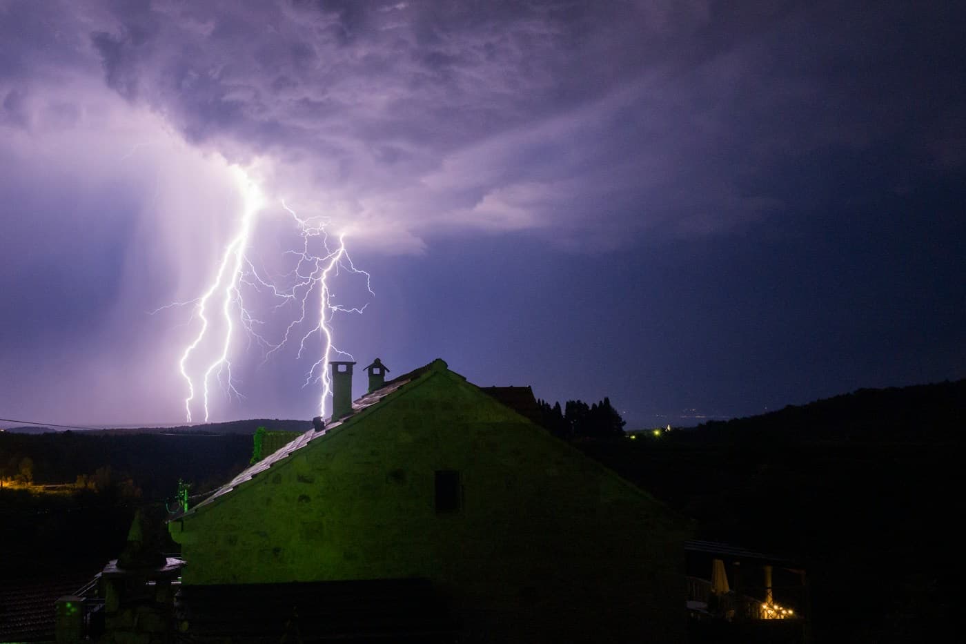 Raios caindo sobre o telhado de uma casa durante a noite