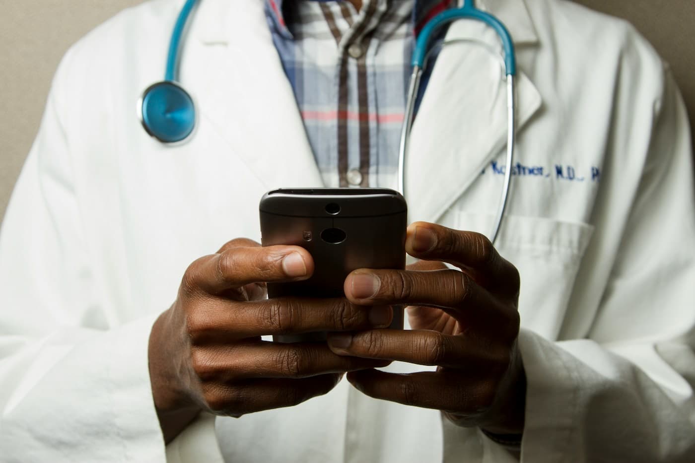 Médico de jaleco usando o celular