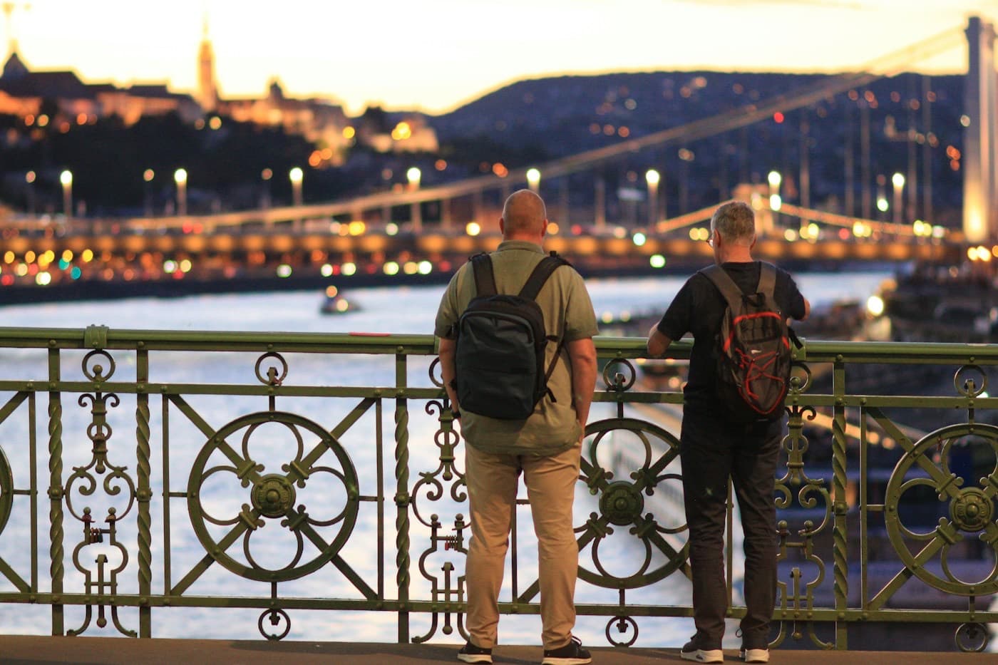 Dois mochileiros observando a cidade iluminada a partir de uma ponte
